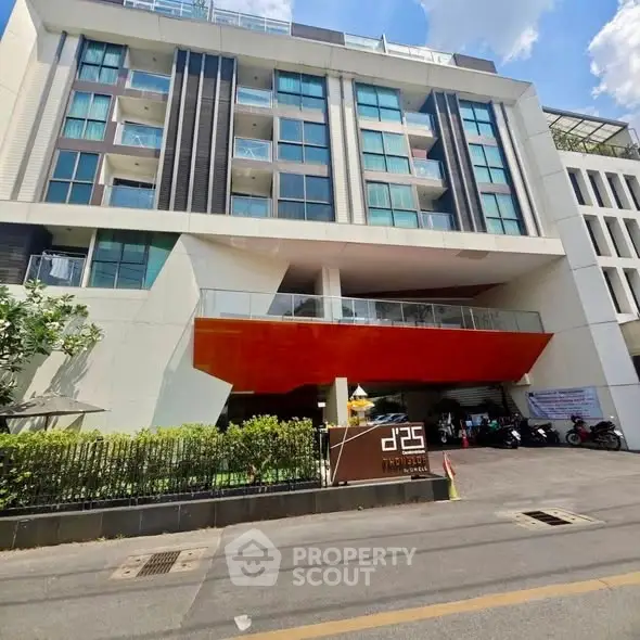 Modern apartment building exterior with sleek design and vibrant orange accents, showcasing urban living.