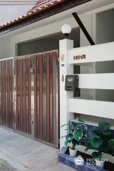 Charming residential entrance with modern gate and potted plants