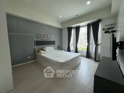 Spacious bedroom with modern decor and large window offering natural light.