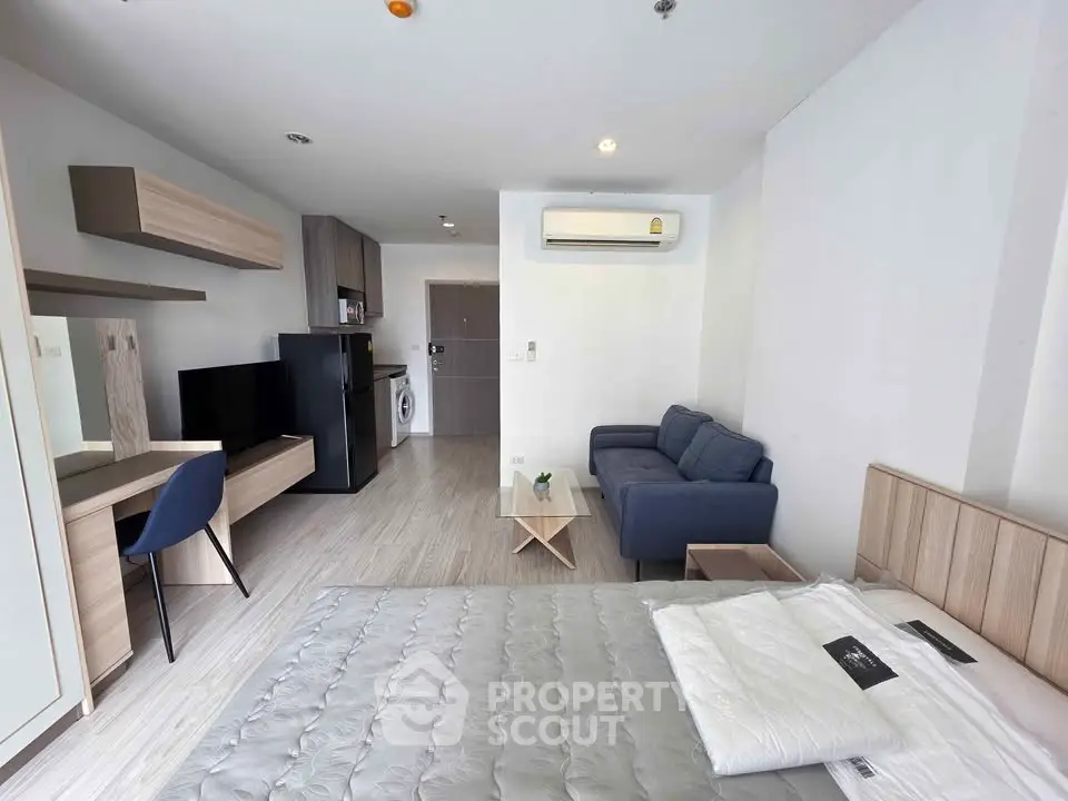Modern studio apartment with sleek furnishings and open layout, featuring a cozy living area and compact kitchen.