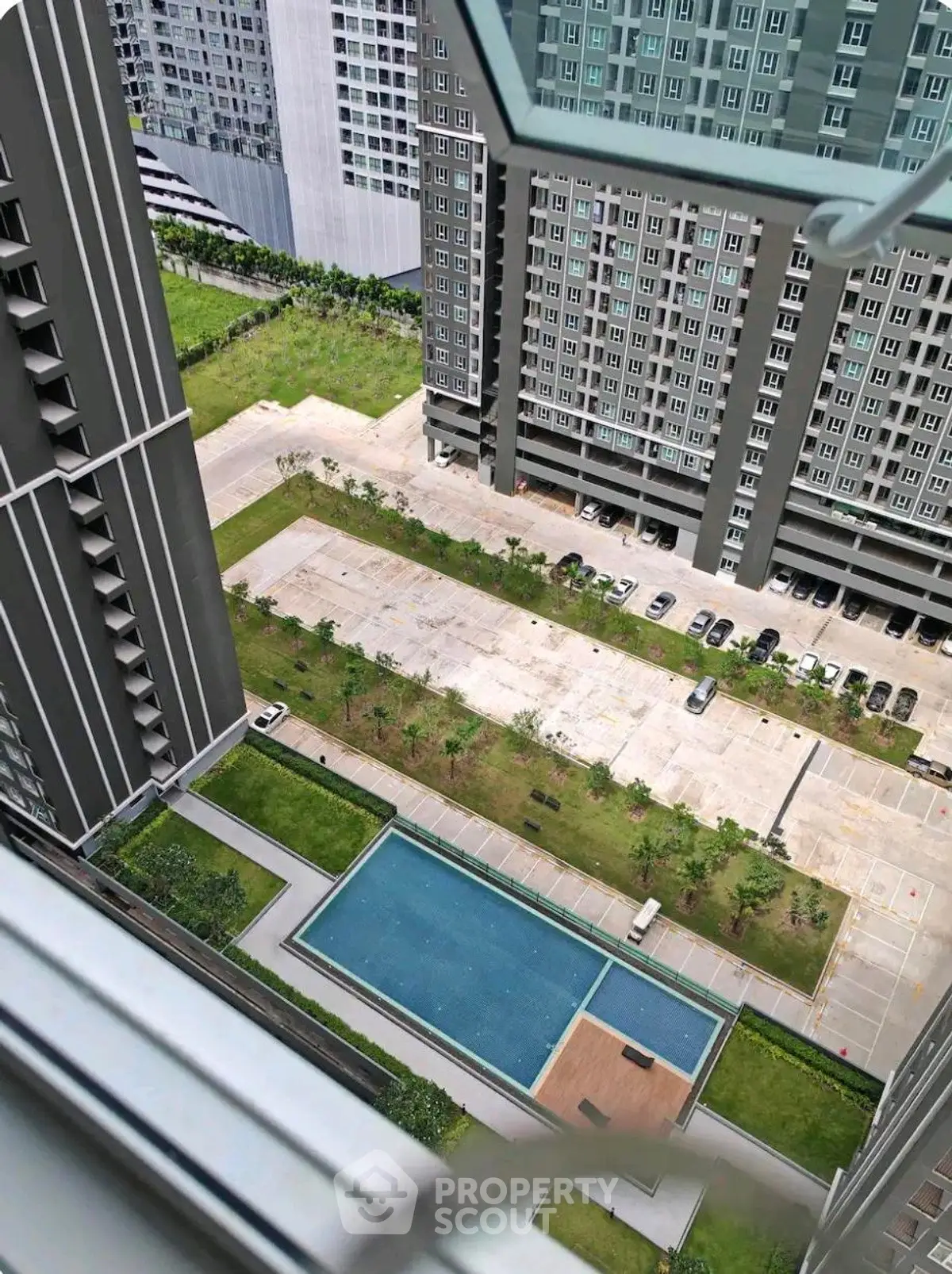High-rise apartment view with pool and parking area, showcasing modern urban living.