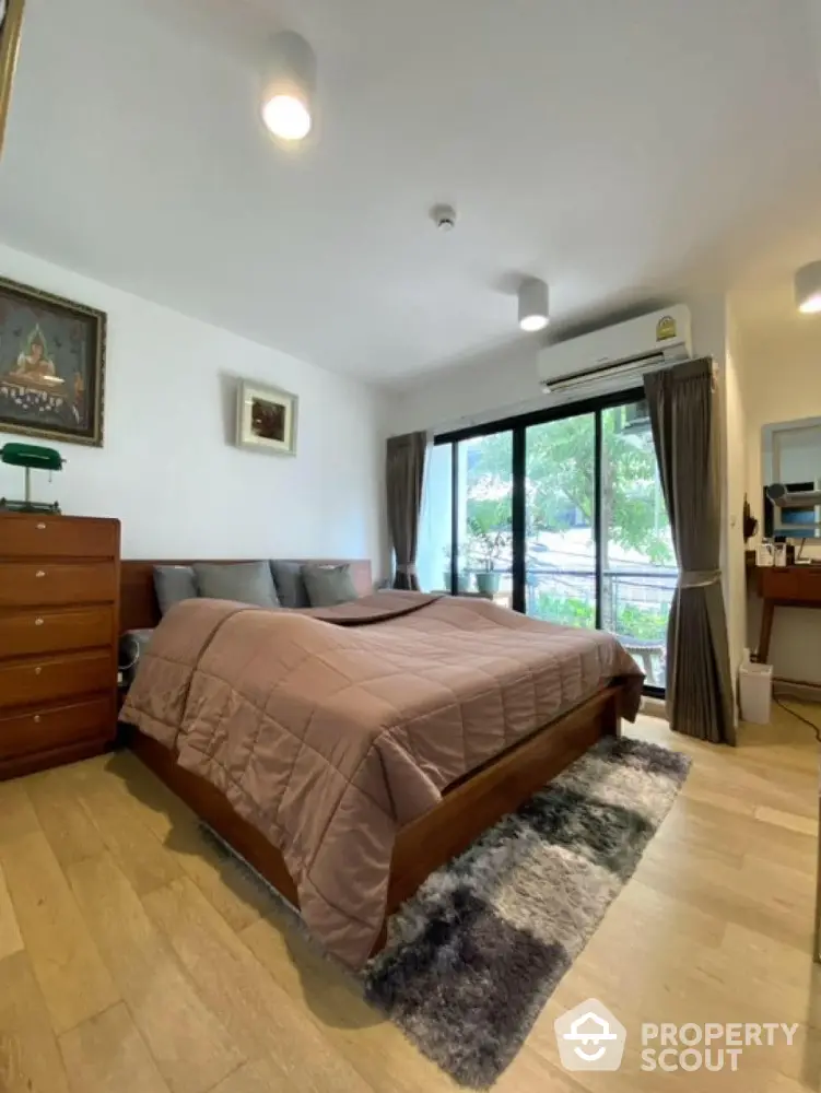 Spacious bedroom with large window and modern decor in a cozy apartment.