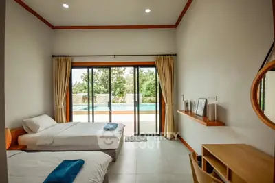 Spacious bedroom with pool view and modern decor, featuring twin beds and natural light.