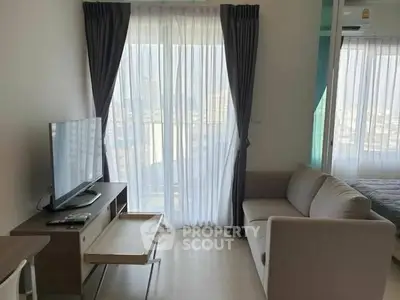 Modern living room with TV and sofa, featuring large windows and city view.