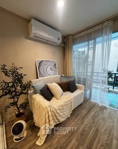 Cozy living room with modern decor and balcony view, featuring air conditioning and stylish furnishings.