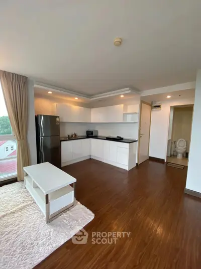 Spacious open-layout kitchen with modern appliances and cozy living area, featuring hardwood floors and natural light.
