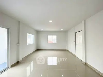 Spacious and bright empty room with glossy tiled floors and large windows, perfect for customization.