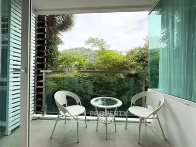 Charming balcony with lush green view and cozy seating area, perfect for relaxation.