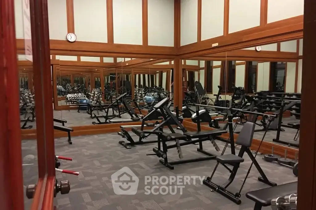 Spacious gym with modern fitness equipment and mirrored walls in a luxury residential building.