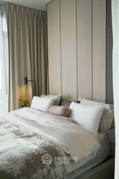 Luxurious bedroom with elegant decor and plush bedding in modern apartment.