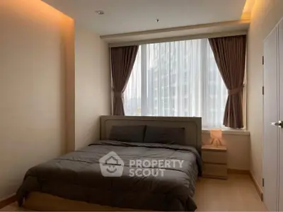 Cozy bedroom with modern decor and large window offering natural light.