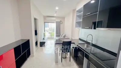 Modern open-layout kitchen and living room with sleek black cabinetry and bright natural light.