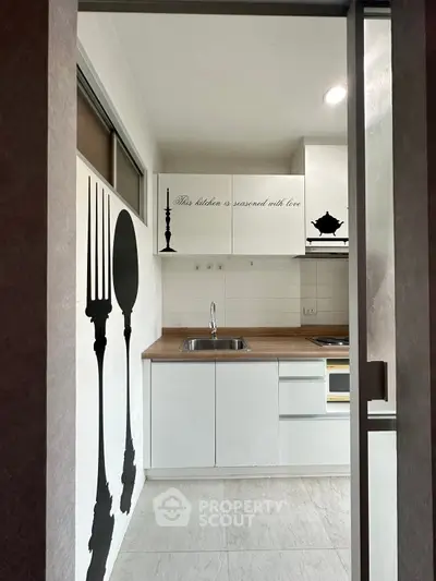 Modern kitchen with white cabinets and decorative wall art, featuring a sleek open layout and contemporary design.
