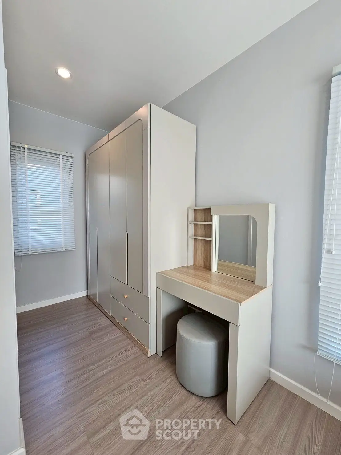 Modern bedroom with sleek wardrobe and stylish vanity in bright natural light.