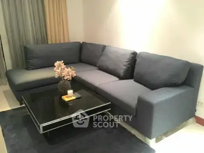 Modern living room with stylish dark blue sectional sofa and sleek black coffee table.