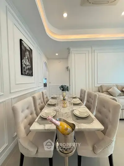 Elegant dining area with marble table and plush chairs in modern living space.