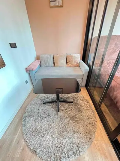 Cozy small living room with modern sofa and glass coffee table on plush rug
