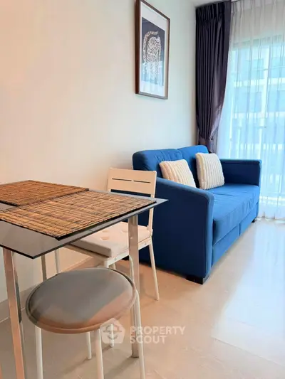 Modern living room with blue sofa and glass dining table in bright apartment