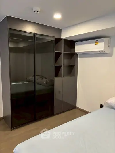 Modern bedroom with sleek black wardrobe and air conditioning unit