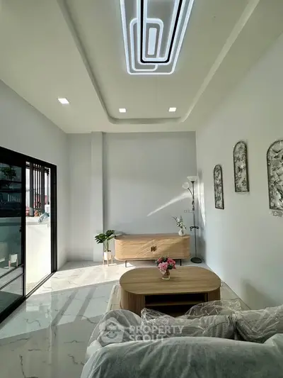 Modern living room with stylish ceiling lights and natural light from large windows.