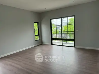 Spacious empty room with large windows and wooden flooring