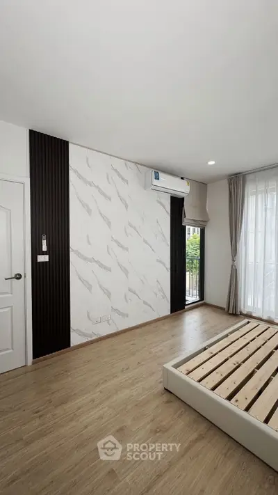 Modern bedroom with stylish accent wall and large window for natural light