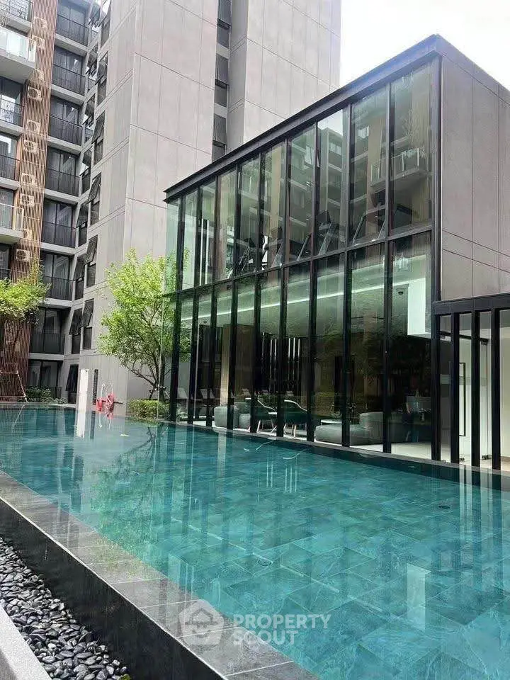 Luxurious modern apartment building with stunning pool and glass facade.