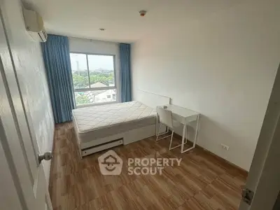 Spacious bedroom with large window and modern furnishings, offering a serene view.