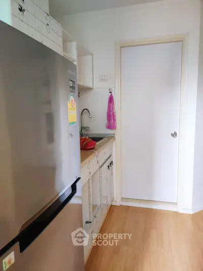 Compact kitchen with stainless steel fridge and wooden flooring