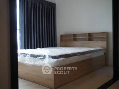 Modern bedroom with new wooden bed frame and large window with dark curtains.