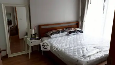 Cozy bedroom with wooden bed frame and natural light from large window, perfect for relaxation.