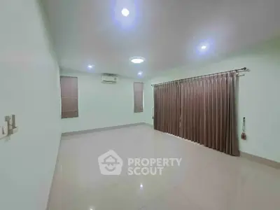 Spacious empty room with glossy tiled floor and large window with curtains.