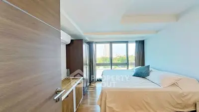 Spacious bedroom with large window offering a scenic view, modern furnishings, and ample natural light.