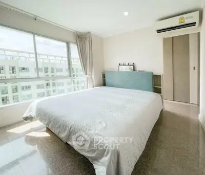 Spacious bedroom with large window and modern decor in a high-rise apartment.