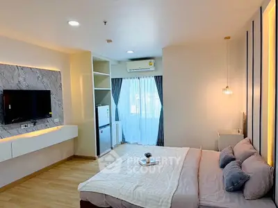 Modern bedroom with stylish decor, featuring a cozy bed, wall-mounted TV, and natural light from large windows.