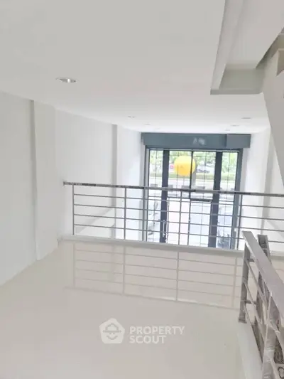 Modern interior with sleek railing and large windows offering natural light