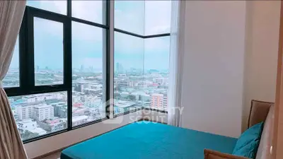Spacious bedroom with panoramic city view from large corner windows.