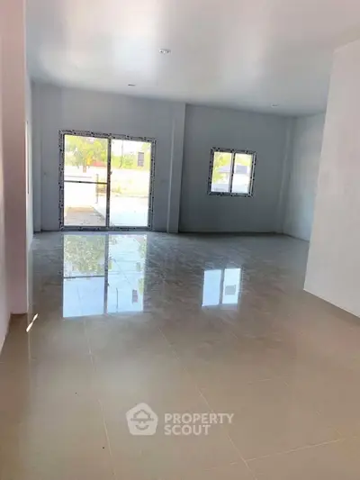 Spacious open-plan living area with large windows and glossy tiled floors.