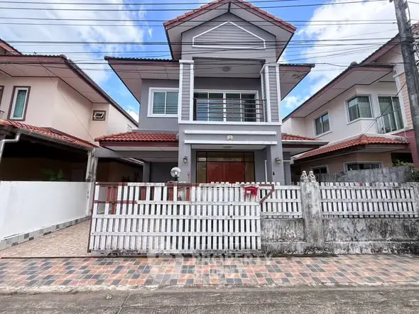 Charming two-story house with tiled roof and gated entrance in a suburban neighborhood.