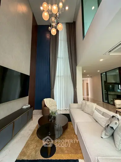 Luxurious modern living room with high ceilings, elegant chandelier, and stylish furniture in a contemporary home.