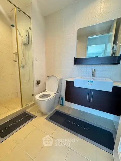 Modern bathroom with glass shower and sleek vanity in a contemporary apartment.