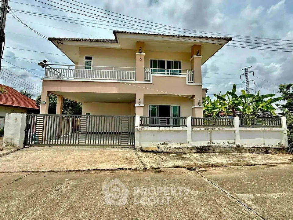 Spacious two-story house with balcony and gated driveway in suburban setting