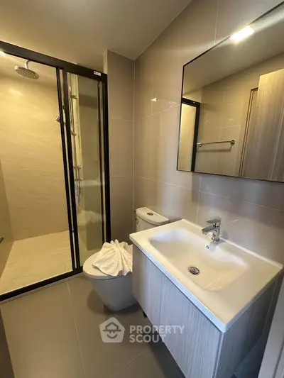Modern bathroom with sleek shower and stylish vanity in contemporary apartment.