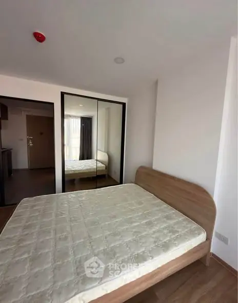 Spacious bedroom with mirrored closet and natural light in modern apartment.