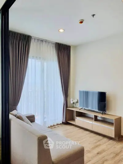 Modern living room with sleek furniture and large window offering natural light.