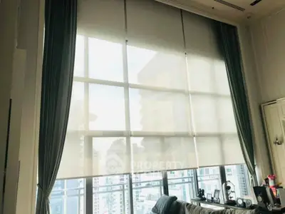 Spacious living room with large windows offering a stunning city view, perfect for urban living.