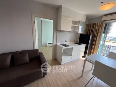 Modern apartment with open kitchen and cozy living area, featuring sleek furniture and a balcony view.