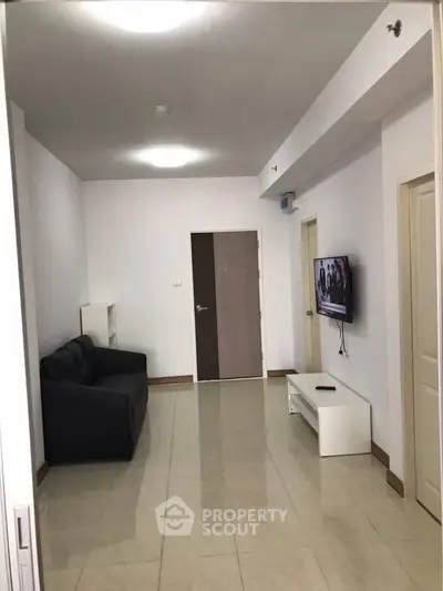 Modern living room with sleek black sofa and wall-mounted TV, perfect for cozy relaxation.