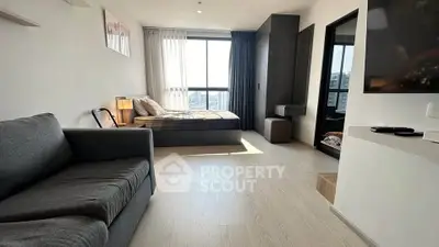 Modern studio apartment with cozy living area and large window view.