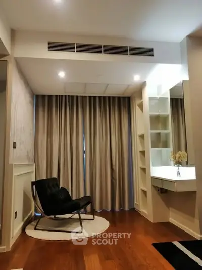 Modern living room with elegant chair and floor-to-ceiling curtains, featuring stylish wooden flooring.